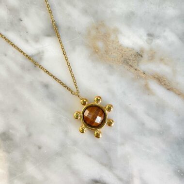 The Starfire Necklace by Sunny Designs combines earthy warmth and celestial design. Handcrafted from brass, this unique piece features a brown stone that symbolizes grounding, stability, and comfort. A perfect addition to natural-toned outfits, offering both elegance and balance.