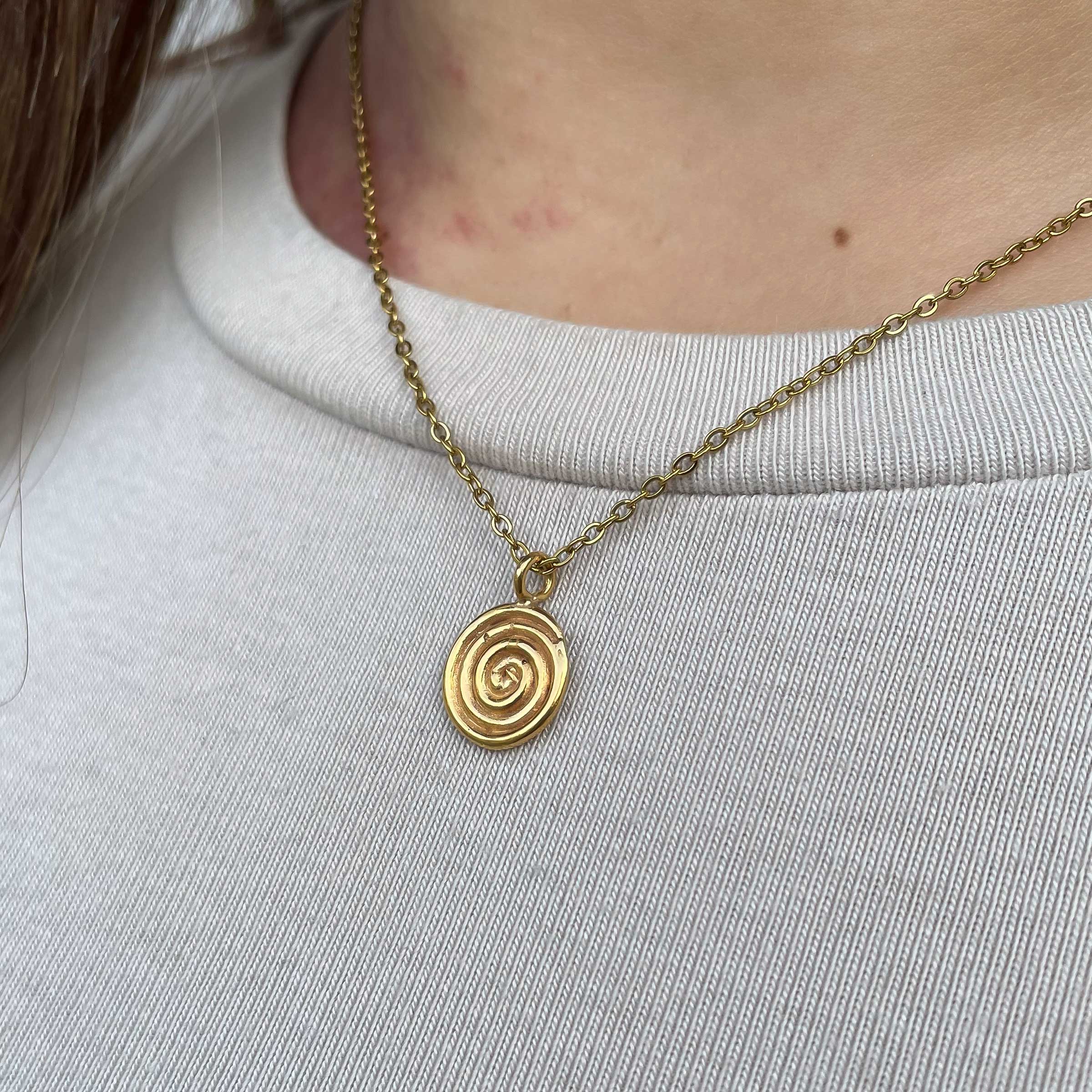 Το Mini Spiral κολιέ της Sunny Designs αποπνέει απλότητα και καλλιτεχνική φινέτσα. Χειροποίητο από υψηλής ποιότητας ορείχαλκο, διαθέτει ένα εκλεπτυσμένο σπειροειδές μενταγιόν — διαχρονικό σύμβολο εξέλιξης και ενέργειας. Ο μίνιμαλ και κομψός σχεδιασμός του το καθιστά ιδανικό για καθημερινή χρήση ή για layering με άλλα κοσμήματα.