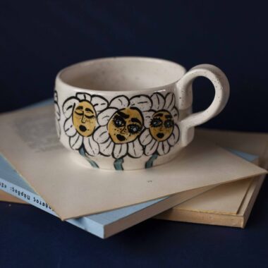 Χειροποίητη κεραμική κούπα διακοσμημένη με ζωγραφιστές μαργαρίτες και πολύχρωμα λουλούδια, όλα με γλυκά προσωπάκια και εκφραστικά μάτια. Πλασμένη και ζωγραφισμένη στο χέρι, κάθε κούπα είναι ένα μοναδικό έργο τέχνης που συνδυάζει τη φρεσκάδα της φύσης με μια παιχνιδιάρικη, ονειρική αισθητική. Ιδανική για όσους αγαπούν τα λουλούδια και τη χειροποίητη δημιουργία. Handmade ceramic mug decorated with painted daisies and colorful flowers, each featuring cute little faces with expressive eyes. Hand-shaped and hand-painted, every mug is a one-of-a-kind piece of art that blends the freshness of nature with a playful, dreamy aesthetic. Perfect for flower lovers and fans of handmade craftsmanship.