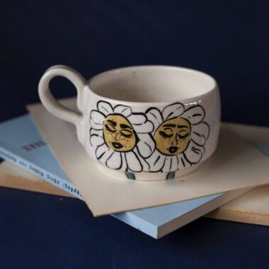 Χειροποίητη κεραμική κούπα διακοσμημένη με ζωγραφιστές μαργαρίτες και πολύχρωμα λουλούδια, όλα με γλυκά προσωπάκια και εκφραστικά μάτια. Πλασμένη και ζωγραφισμένη στο χέρι, κάθε κούπα είναι ένα μοναδικό έργο τέχνης που συνδυάζει τη φρεσκάδα της φύσης με μια παιχνιδιάρικη, ονειρική αισθητική. Ιδανική για όσους αγαπούν τα λουλούδια και τη χειροποίητη δημιουργία. Handmade ceramic mug decorated with painted daisies and colorful flowers, each featuring cute little faces with expressive eyes. Hand-shaped and hand-painted, every mug is a one-of-a-kind piece of art that blends the freshness of nature with a playful, dreamy aesthetic. Perfect for flower lovers and fans of handmade craftsmanship.