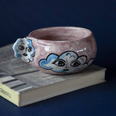Handmade ceramic mug with a cloud-shaped handle and painted cloud faces featuring shiny eyes in an angelic core aesthetic. Soft blue and pink tones create a dreamy, sweet atmosphere. Each mug is one of a kind — hand-shaped and hand-painted, a small personal piece of art for those who love unique creations. Χειροποίητη κεραμική κούπα με χερούλι σε σχήμα συννεφιού και ζωγραφιστά συννεφάκια με εκφραστικά προσωπάκια και γυαλιστερά μάτια σε angelic core αισθητική. Οι απαλοί τόνοι του γαλάζιου και του ροζ προσδίδουν μια ονειρική, γλυκιά αίσθηση. Κάθε κούπα είναι μοναδική, πλασμένη και ζωγραφισμένη στο χέρι, ένα μικρό προσωπικό έργο τέχνης για κάθε λάτρη των ιδιαίτερων αντικειμένων.