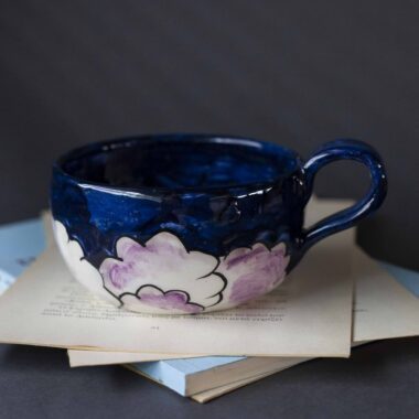 Handmade ceramic mug with a cloud-shaped handle and painted cloud faces featuring shiny eyes in an angelic core aesthetic. Soft blue and pink tones create a dreamy, sweet atmosphere. Each mug is one of a kind — hand-shaped and hand-painted, a small personal piece of art for those who love unique creations. Χειροποίητη κεραμική κούπα με χερούλι σε σχήμα συννεφιού και ζωγραφιστά συννεφάκια με εκφραστικά προσωπάκια και γυαλιστερά μάτια σε angelic core αισθητική. Οι απαλοί τόνοι του γαλάζιου και του ροζ προσδίδουν μια ονειρική, γλυκιά αίσθηση. Κάθε κούπα είναι μοναδική, πλασμένη και ζωγραφισμένη στο χέρι, ένα μικρό προσωπικό έργο τέχνης για κάθε λάτρη των ιδιαίτερων αντικειμένων.