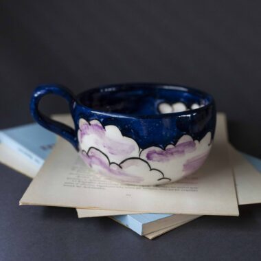 Handmade ceramic mug with a cloud-shaped handle and painted cloud faces featuring shiny eyes in an angelic core aesthetic. Soft blue and pink tones create a dreamy, sweet atmosphere. Each mug is one of a kind — hand-shaped and hand-painted, a small personal piece of art for those who love unique creations. Χειροποίητη κεραμική κούπα με χερούλι σε σχήμα συννεφιού και ζωγραφιστά συννεφάκια με εκφραστικά προσωπάκια και γυαλιστερά μάτια σε angelic core αισθητική. Οι απαλοί τόνοι του γαλάζιου και του ροζ προσδίδουν μια ονειρική, γλυκιά αίσθηση. Κάθε κούπα είναι μοναδική, πλασμένη και ζωγραφισμένη στο χέρι, ένα μικρό προσωπικό έργο τέχνης για κάθε λάτρη των ιδιαίτερων αντικειμένων.