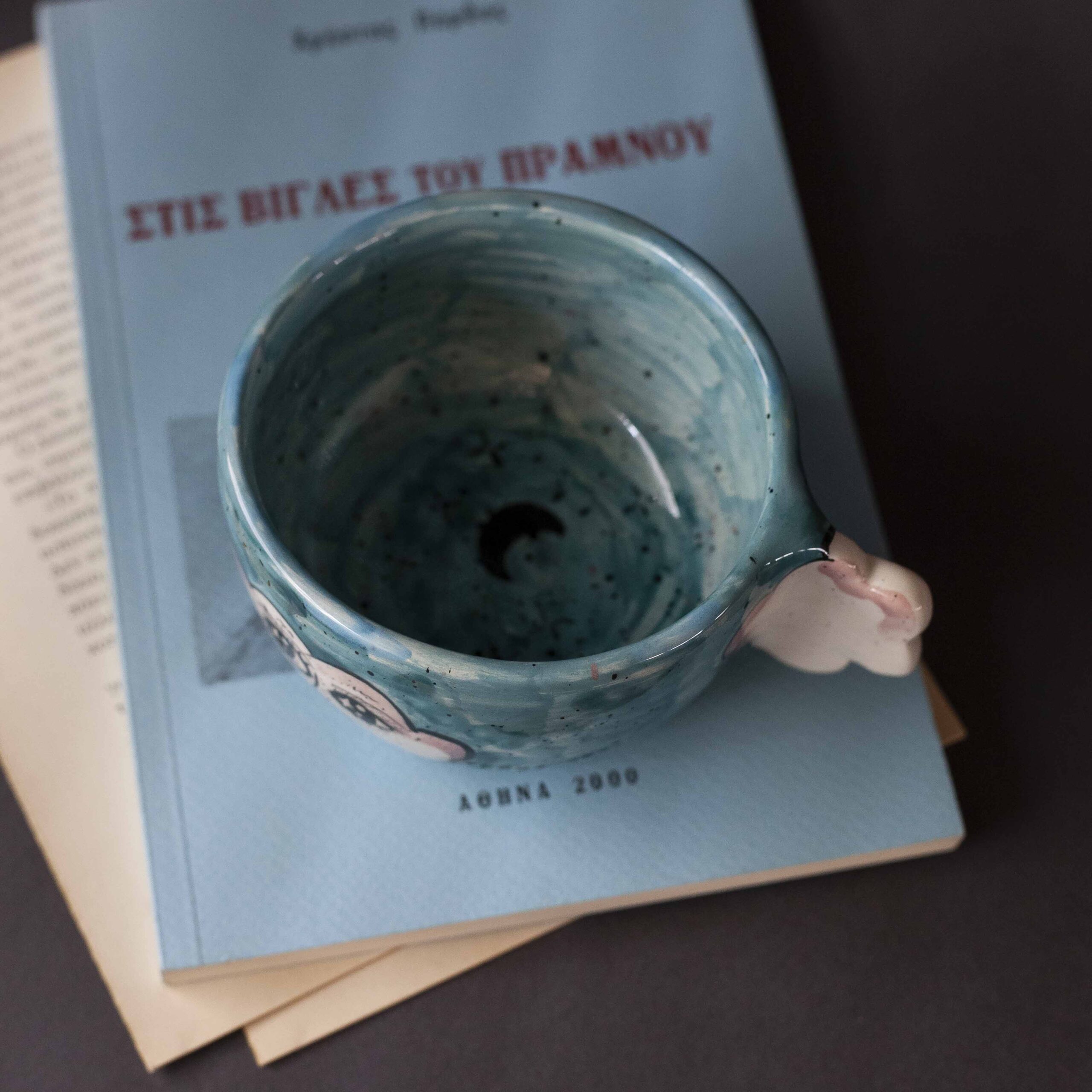 Handmade ceramic mug with a cloud-shaped handle and painted cloud faces featuring shiny eyes in an angelic core aesthetic. Soft blue and pink tones create a dreamy, sweet atmosphere. Each mug is one of a kind — hand-shaped and hand-painted, a small personal piece of art for those who love unique creations. Χειροποίητη κεραμική κούπα με χερούλι σε σχήμα συννεφιού και ζωγραφιστά συννεφάκια με εκφραστικά προσωπάκια και γυαλιστερά μάτια σε angelic core αισθητική. Οι απαλοί τόνοι του γαλάζιου και του ροζ προσδίδουν μια ονειρική, γλυκιά αίσθηση. Κάθε κούπα είναι μοναδική, πλασμένη και ζωγραφισμένη στο χέρι, ένα μικρό προσωπικό έργο τέχνης για κάθε λάτρη των ιδιαίτερων αντικειμένων.