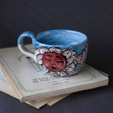 Χειροποίητη κεραμική κούπα διακοσμημένη με ζωγραφιστές μαργαρίτες και πολύχρωμα λουλούδια, όλα με γλυκά προσωπάκια και εκφραστικά μάτια. Πλασμένη και ζωγραφισμένη στο χέρι, κάθε κούπα είναι ένα μοναδικό έργο τέχνης που συνδυάζει τη φρεσκάδα της φύσης με μια παιχνιδιάρικη, ονειρική αισθητική. Ιδανική για όσους αγαπούν τα λουλούδια και τη χειροποίητη δημιουργία. Handmade ceramic mug decorated with painted daisies and colorful flowers, each featuring cute little faces with expressive eyes. Hand-shaped and hand-painted, every mug is a one-of-a-kind piece of art that blends the freshness of nature with a playful, dreamy aesthetic. Perfect for flower lovers and fans of handmade craftsmanship.