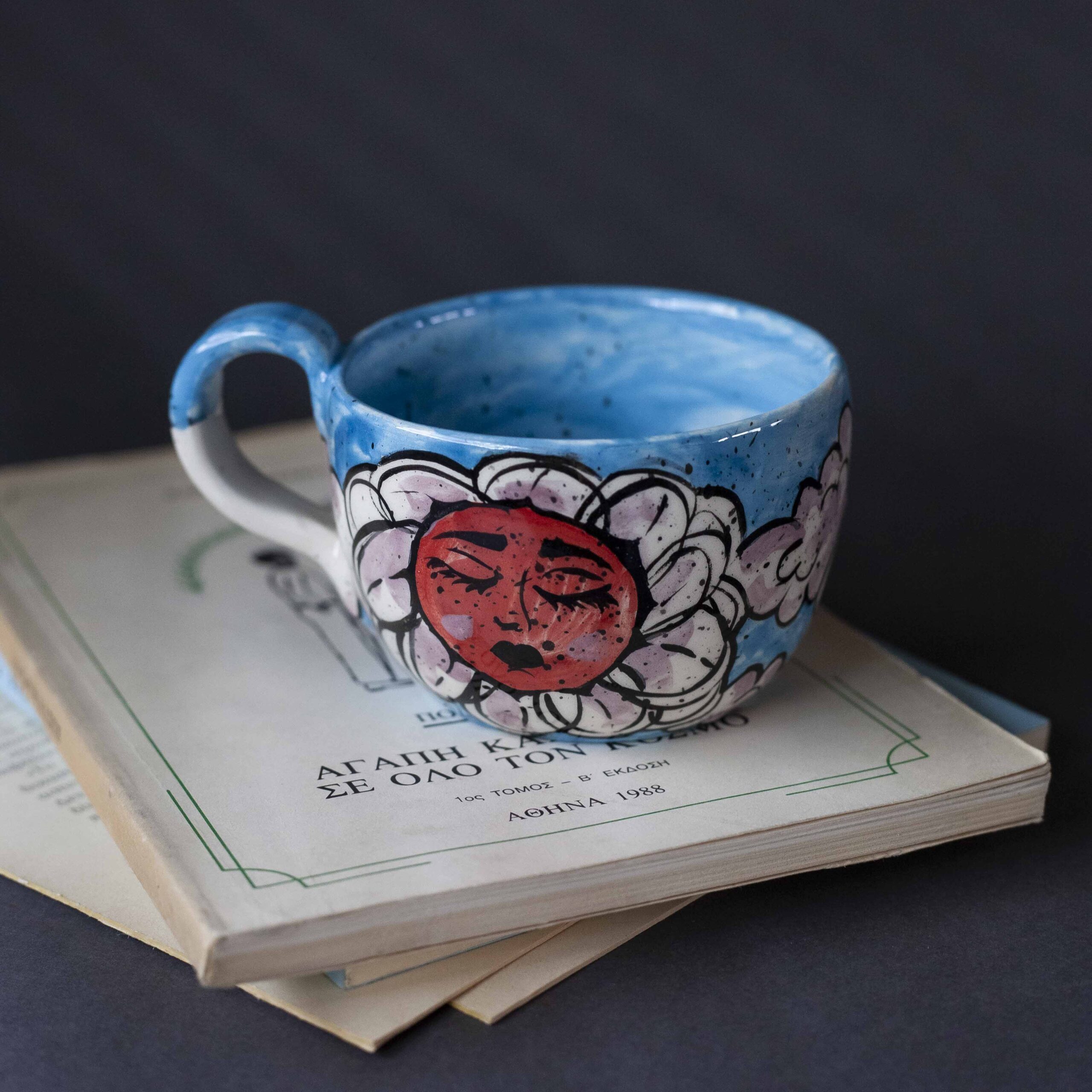 Χειροποίητη κεραμική κούπα διακοσμημένη με ζωγραφιστές μαργαρίτες και πολύχρωμα λουλούδια, όλα με γλυκά προσωπάκια και εκφραστικά μάτια. Πλασμένη και ζωγραφισμένη στο χέρι, κάθε κούπα είναι ένα μοναδικό έργο τέχνης που συνδυάζει τη φρεσκάδα της φύσης με μια παιχνιδιάρικη, ονειρική αισθητική. Ιδανική για όσους αγαπούν τα λουλούδια και τη χειροποίητη δημιουργία. Handmade ceramic mug decorated with painted daisies and colorful flowers, each featuring cute little faces with expressive eyes. Hand-shaped and hand-painted, every mug is a one-of-a-kind piece of art that blends the freshness of nature with a playful, dreamy aesthetic. Perfect for flower lovers and fans of handmade craftsmanship.