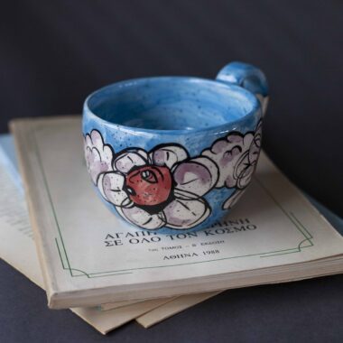 Χειροποίητη κεραμική κούπα διακοσμημένη με ζωγραφιστές μαργαρίτες και πολύχρωμα λουλούδια, όλα με γλυκά προσωπάκια και εκφραστικά μάτια. Πλασμένη και ζωγραφισμένη στο χέρι, κάθε κούπα είναι ένα μοναδικό έργο τέχνης που συνδυάζει τη φρεσκάδα της φύσης με μια παιχνιδιάρικη, ονειρική αισθητική. Ιδανική για όσους αγαπούν τα λουλούδια και τη χειροποίητη δημιουργία. Handmade ceramic mug decorated with painted daisies and colorful flowers, each featuring cute little faces with expressive eyes. Hand-shaped and hand-painted, every mug is a one-of-a-kind piece of art that blends the freshness of nature with a playful, dreamy aesthetic. Perfect for flower lovers and fans of handmade craftsmanship.