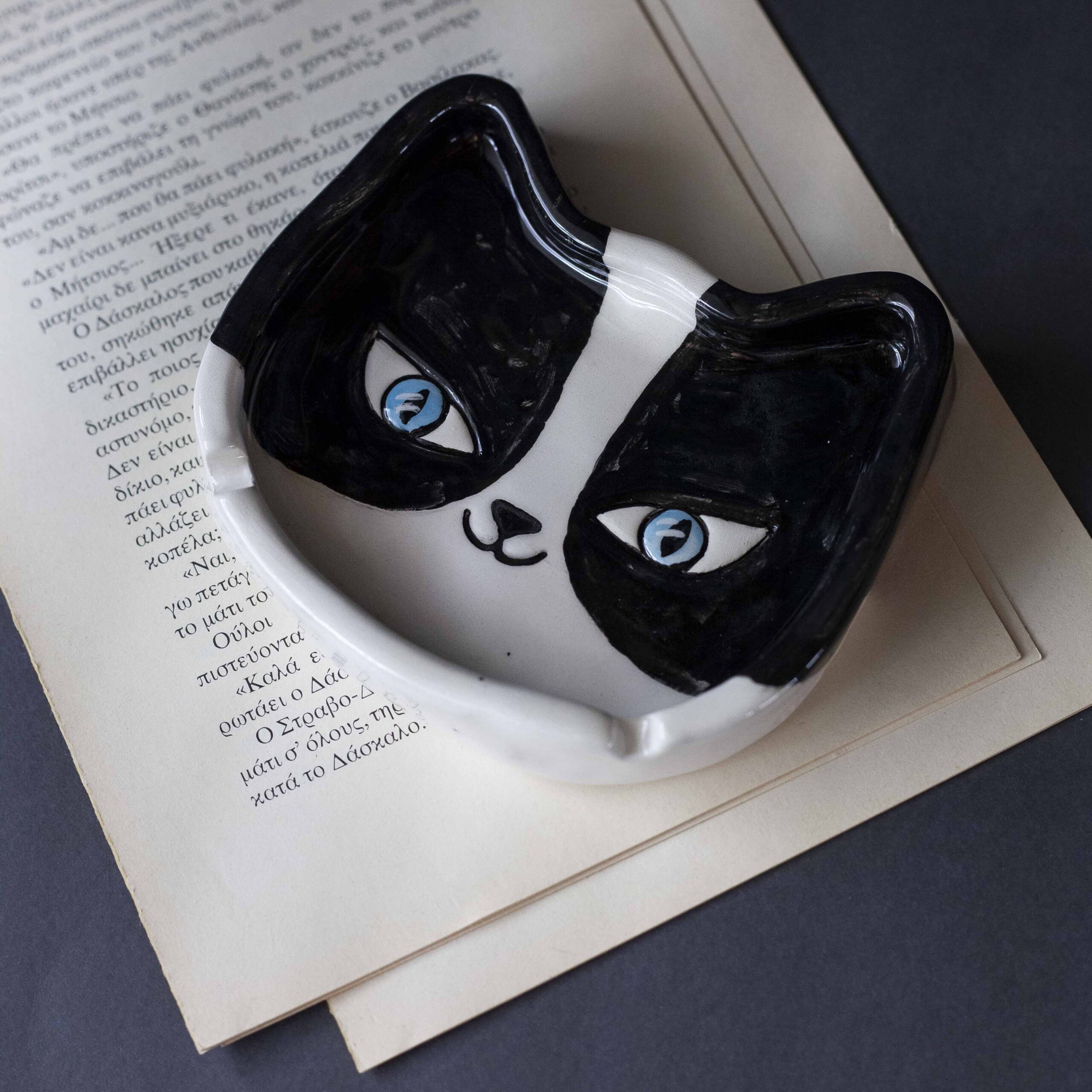 Χειροποίητα κεραμικά τασάκια και κούπες με σχέδια γατών, κάθε μία με ξεχωριστή έκφραση και χαρακτήρα. Πλασμένες και ζωγραφισμένες στο χέρι με ζωηρά χρώματα και καλλιτεχνικές λεπτομέρειες, ιδανικές για τους λάτρεις των γατών και της χειροποίητης τέχνης. Handmade ceramic cat-themed ashtrays and mugs, each featuring unique cat expressions and artistic charm. Hand-shaped and hand-painted with lively colors and creative details — perfect for cat lovers and fans of handmade artistry.