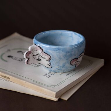 Handmade ceramic mug with a cloud-shaped handle and painted cloud faces featuring shiny eyes in an angelic core aesthetic. Soft blue and pink tones create a dreamy, sweet atmosphere. Each mug is one of a kind — hand-shaped and hand-painted, a small personal piece of art for those who love unique creations. Χειροποίητη κεραμική κούπα με χερούλι σε σχήμα συννεφιού και ζωγραφιστά συννεφάκια με εκφραστικά προσωπάκια και γυαλιστερά μάτια σε angelic core αισθητική. Οι απαλοί τόνοι του γαλάζιου και του ροζ προσδίδουν μια ονειρική, γλυκιά αίσθηση. Κάθε κούπα είναι μοναδική, πλασμένη και ζωγραφισμένη στο χέρι, ένα μικρό προσωπικό έργο τέχνης για κάθε λάτρη των ιδιαίτερων αντικειμένων.
