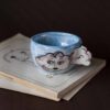 Handmade ceramic mug with a cloud-shaped handle and painted cloud faces featuring shiny eyes in an angelic core aesthetic. Soft blue and pink tones create a dreamy, sweet atmosphere. Each mug is one of a kind — hand-shaped and hand-painted, a small personal piece of art for those who love unique creations. Χειροποίητη κεραμική κούπα με χερούλι σε σχήμα συννεφιού και ζωγραφιστά συννεφάκια με εκφραστικά προσωπάκια και γυαλιστερά μάτια σε angelic core αισθητική. Οι απαλοί τόνοι του γαλάζιου και του ροζ προσδίδουν μια ονειρική, γλυκιά αίσθηση. Κάθε κούπα είναι μοναδική, πλασμένη και ζωγραφισμένη στο χέρι, ένα μικρό προσωπικό έργο τέχνης για κάθε λάτρη των ιδιαίτερων αντικειμένων.