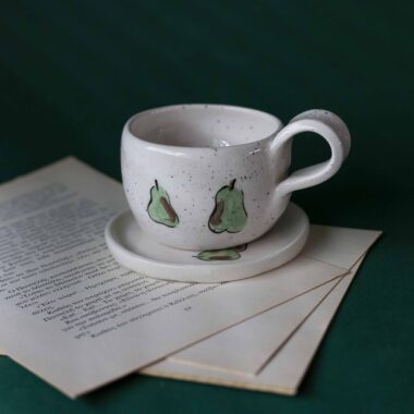 Χειροποίητα κεραμικά εσπρέσο κουπάκια με πιατάκι, διακοσμημένα με ζωγραφιστά φρουτάκια — πορτοκάλια, λεμόνια και αχλάδια — ανάμεσα σε μικρά λουλουδάκια. Οι δίχρωμοι συνδυασμοί και οι λεπτομέρειες στο χέρι χαρίζουν παιχνιδιάρικη και ζωντανή αισθητική. Κάθε σετ είναι μοναδικό, πλασμένο και ζωγραφισμένο στο χέρι, ιδανικό για να προσθέσει χρώμα και τέχνη σε κάθε στιγμή καφέ. Handmade ceramic espresso cup and saucer set, decorated with hand-painted fruits — oranges, lemons, and pears — surrounded by small flowers. The two-tone color combinations and fine hand-painted details give a lively, playful feel. Each set is one of a kind, crafted and painted by hand, perfect for adding a splash of color and artistry to your coffee moments.