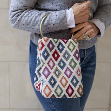 χειροποίητη τσάντα σε λευκό χρώμα με μεγάλο χρυσό κρίκο για χερούλι. Το μοτίβο της είναι πολύχρωμοι ρόμβοι. Handmadebag in white color with a big golden hoop as a handle. Her pattern in colorful rhombus.