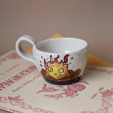 χειροποίητη κεραμική κούπα με πηλό υψηλής θερμοκρασίας και τον κάλσιφερ πάνω της. handmade ceramic mug with high temperature clay and calcifer on it.