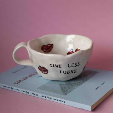 Χειροποίητη κεραμική κούπα με μήνυμα give less fucks και φιλάκια, χιουμοριστικό και statement σχέδιο Handmade ceramic mug with “give less fucks” text and kisses, bold and playful pottery design