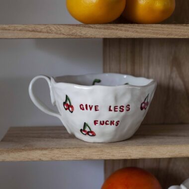 χειροποίητη κεραμική τσιμπητή κούπα με κεράσια ζωγραφισμένα που γράφει give less fucks handmade mug that writes give less fucks and has on it and has cherries painted.