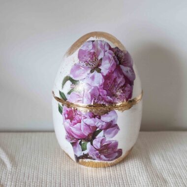 Ρομαντικό χειροποίητο διακοσμητικό αυγό με εντυπωσιακή σύνθεση από ροζ ανθισμένα λουλούδια. Η διακριτική χρήση φύλλου χρυσού προσθέτει λάμψη και πολυτέλεια, δημιουργώντας ένα κομψό αποτέλεσμα που ξεχωρίζει. Ιδανικό για πασχαλινή διακόσμηση, ανοιξιάτικες συνθέσεις ή ως ιδιαίτερο δώρο.