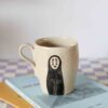 Tall handmade ceramic mug with No-Face and soot sprites design, beige speckled clay, high-fired pottery Ψηλή χειροποίητη κεραμική κούπα με τον Απρόσωπο και καπνόμπαλες, μπεζ πηλός με σαμότ, υψηλής θερμοκρασίας