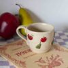 Handmade ceramic mug with 3D apples and pears, beige speckled clay, textured fruit design Χειροποίητη κεραμική κούπα με 3D μήλα και αχλάδια, μπεζ πηλός με σαμότ, ανάγλυφο σχέδιο