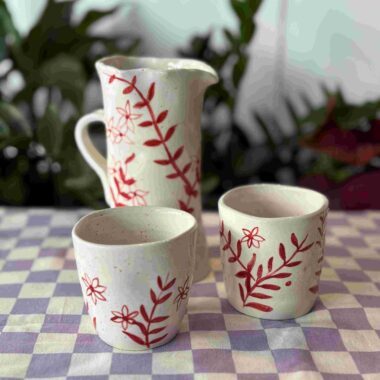 handmade ceramic red set with red florals. it has a jug and two cups. χειροποίητο κεραμικό σετ που αποτελείται από κανάτα και δύο ποτήρια. σε κόκκινες φλοράλ αποχρώσεις.