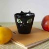 χειροποίητη κούπα με πρόσωπο μαύρης γάτας . handmade black cat mug with snout and green eyes. perfect for coffee and tea.