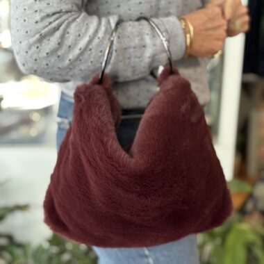 handmade fake fur bag in red color with two hoops for handle.