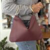 handmade leather bag in red color with hoop handles. χειροποίητη δερμάτινη τσάντα σε κόκκινο χρώμα με δύο μεταλλικούς κρίκους για χερούλι.