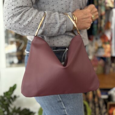 handmade leather bag in red color with hoop handles. χειροποίητη δερμάτινη τσάντα σε κόκκινο χρώμα με δύο μεταλλικούς κρίκους για χερούλι.